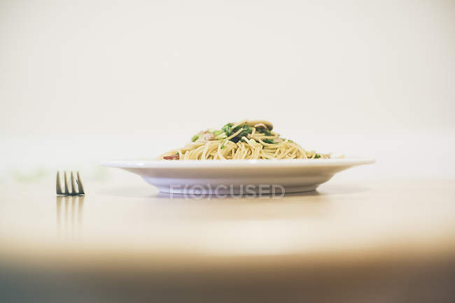 Placa de porção de macarrão na mesa com garfo — Fotografia de Stock