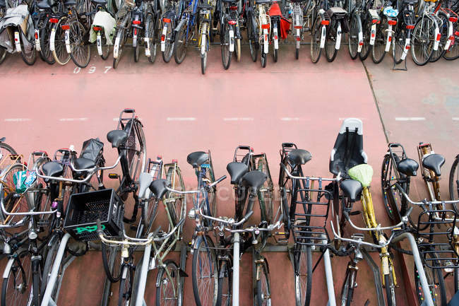 Bicicletas estacionadas en fila en la carretera, Amsterdam, Países Bajos - foto de stock