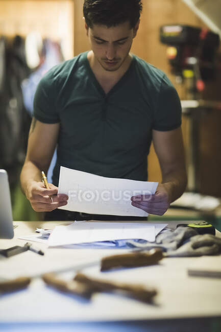 Молодой человек держит бумажную работу, смотрит вниз — стоковое фото