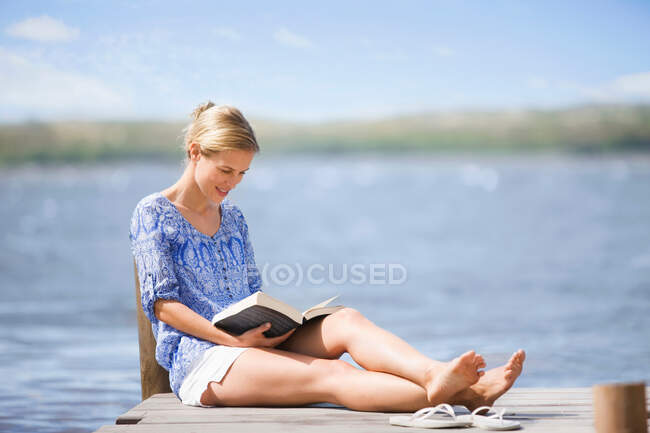 Mulher lendo um livro lago-lado — Fotografia de Stock