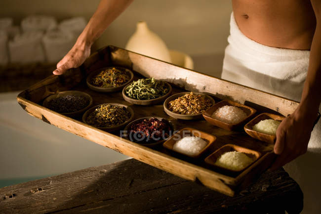 Cropped image of man holding tray with herbs and salt — Stock Photo