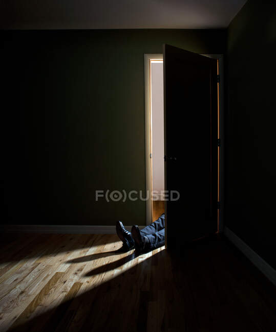 Бізнесмен лежить у дверному отворі темної кімнати — стокове фото