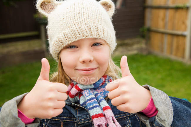 Smiling girl giving thumbs-up outdoors — Stock Photo