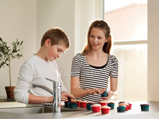 Children decorating cupcakes together — Stock Photo