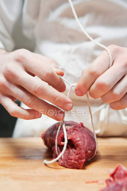 Butcher tying beef tenderloin with string — Stock Photo