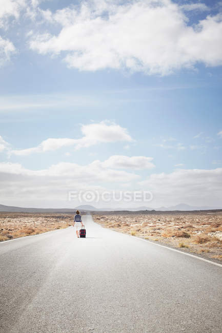 Жінка рухомий багаж на сільській дорозі — стокове фото
