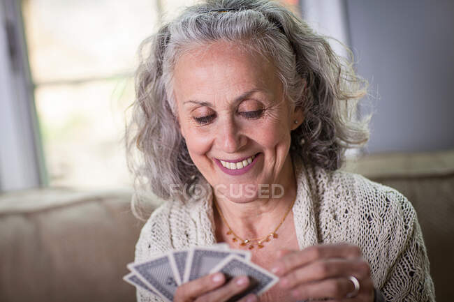Donna anziana che gioca a carte a casa — Foto stock