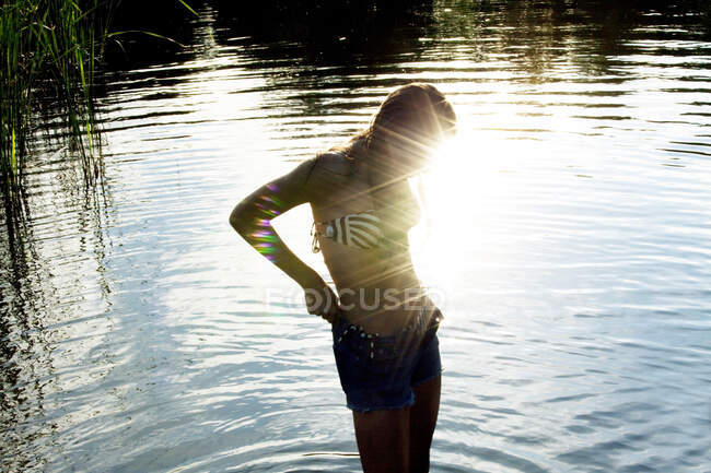 Teenage girl standing in sunlit river — Stock Photo