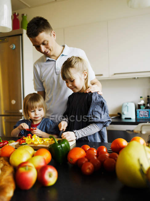 Pai e filhas cortando pimentas — Fotografia de Stock