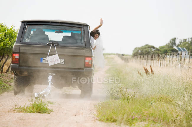 Newlywed woman waving from vehicle — Stock Photo