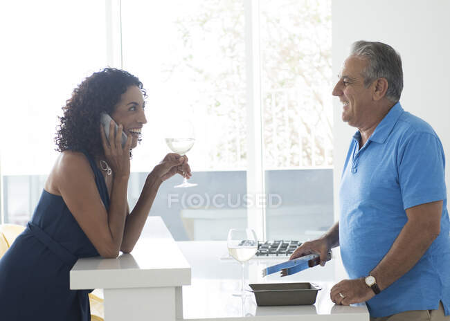Senior homme et femme en utilisant smartphone au comptoir de la cuisine — Photo de stock