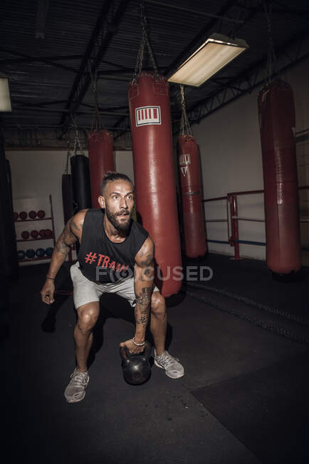 Male boxer preparing to lift kettlebell in gym — Stock Photo