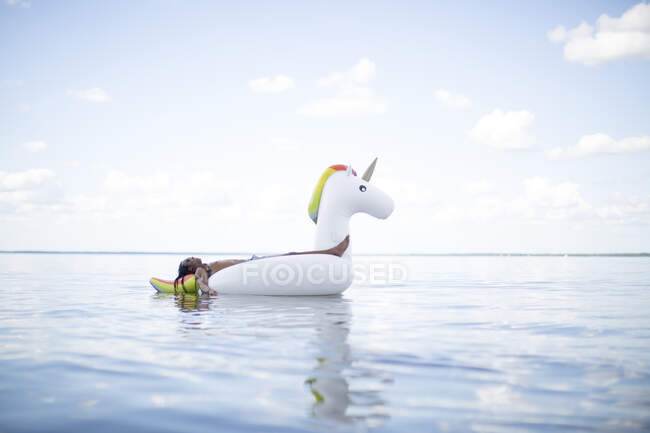 Young man lying back on inflatable unicorn in sea, Santa Rosa Beach, Florida, USA — Stock Photo