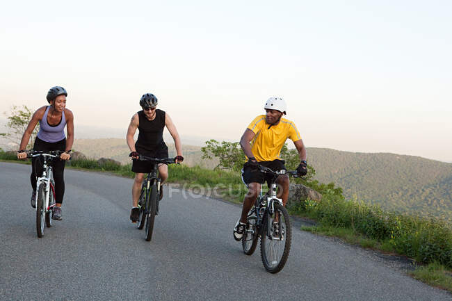 Tres ciclistas en la carretera - foto de stock
