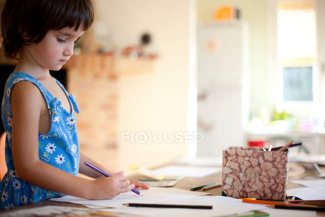 Маленькая девочка рисунок за кухонным столом — стоковое фото