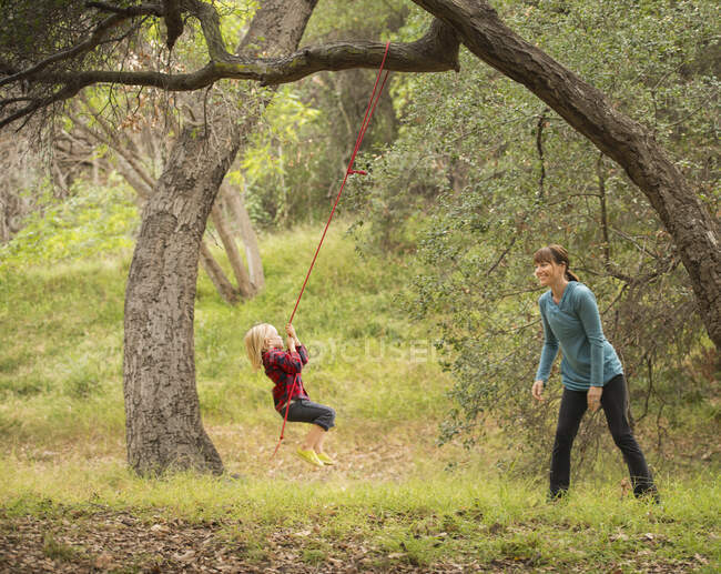 Mãe empurrando filho no balanço da árvore — Fotografia de Stock