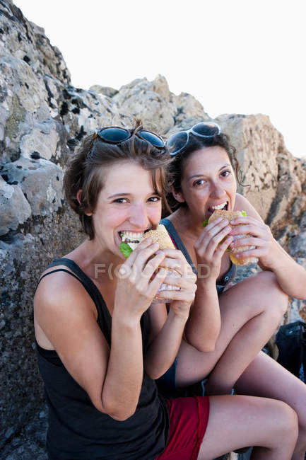 Los excursionistas comiendo sándwiches en rocas, se centran en el primer plano - foto de stock