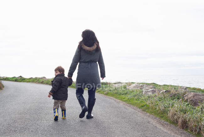 Madre e hijo caminando por el camino rural - foto de stock