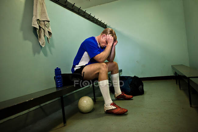 Soccer player in changing room with head in hands — Stock Photo
