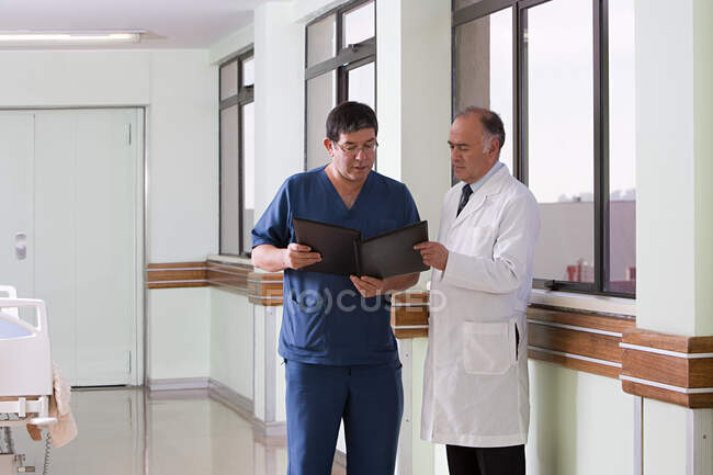 Médico y cirujano mirando el archivo - foto de stock