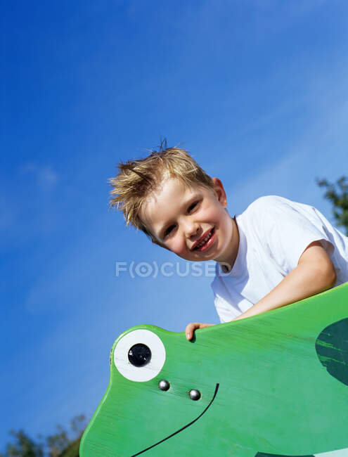 Rapaz feliz montando sapo de madeira. — Fotografia de Stock