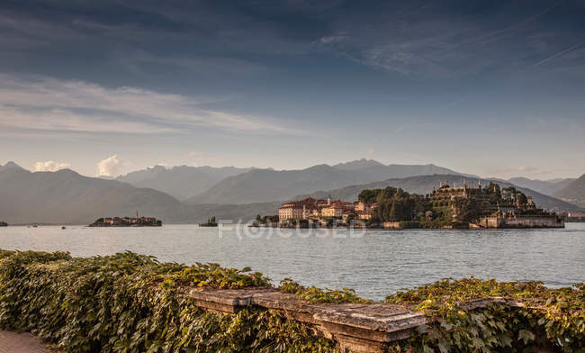 Old village buildings on island in lake with hills on background — Stock Photo
