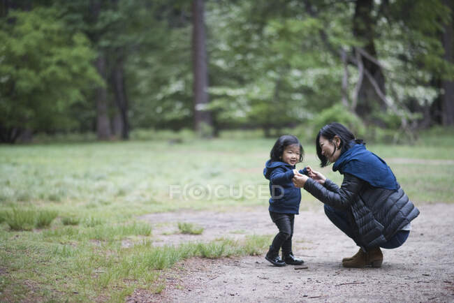 Mid adult woman crouching with toddler daughter on forest path, Yosemite National Park, California, USA — Stock Photo