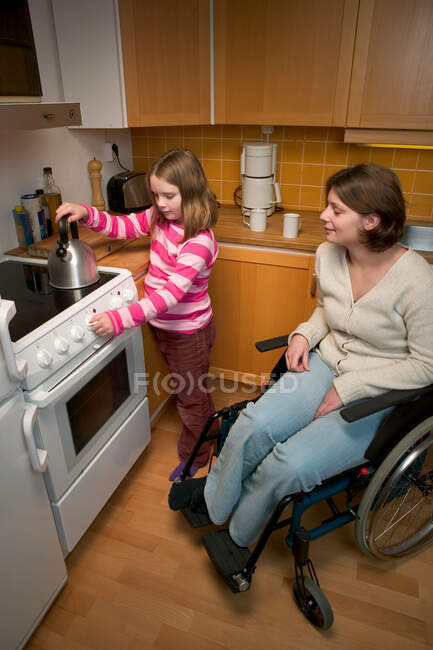 Disabled mother and daughter in kitchen — Stock Photo