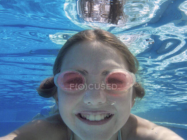 Close up underwater portrait of girl wearing goggles in swimming pool — Stock Photo