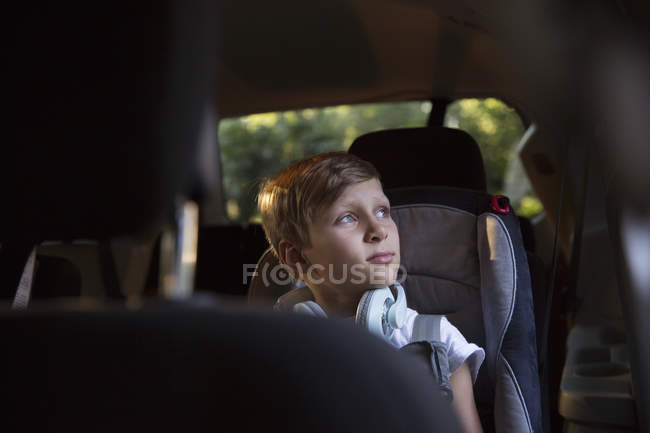 Garçon dans le siège arrière de voiture regardant par la fenêtre — Photo de stock