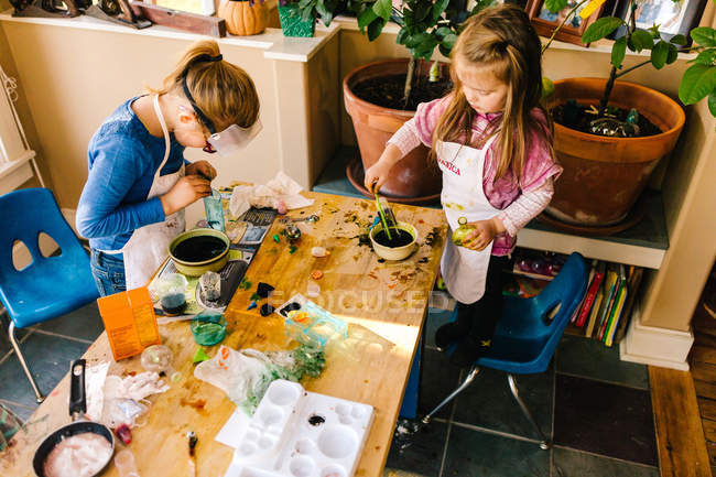 Deux filles faisant des expériences scientifiques à une table en désordre — Photo de stock