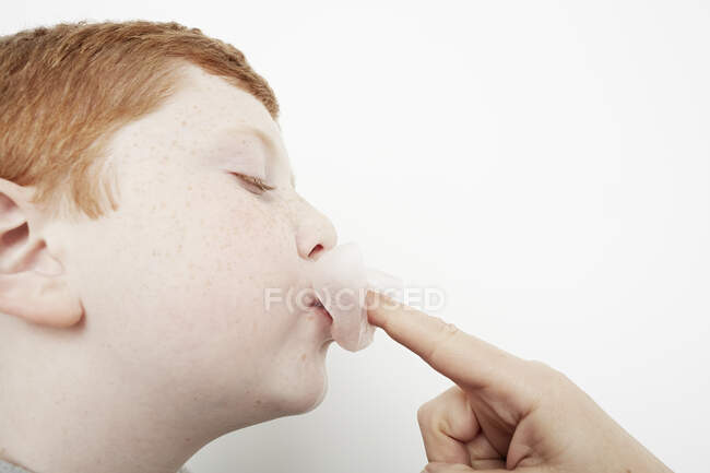 Chico pegando goma de mascar de nuevo en su boca - foto de stock
