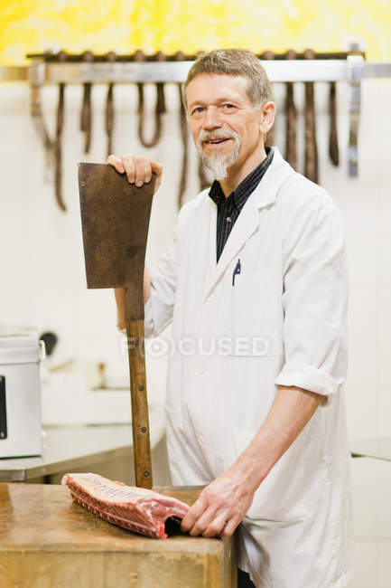 Açougueiro segurando faca grande e carne — Fotografia de Stock
