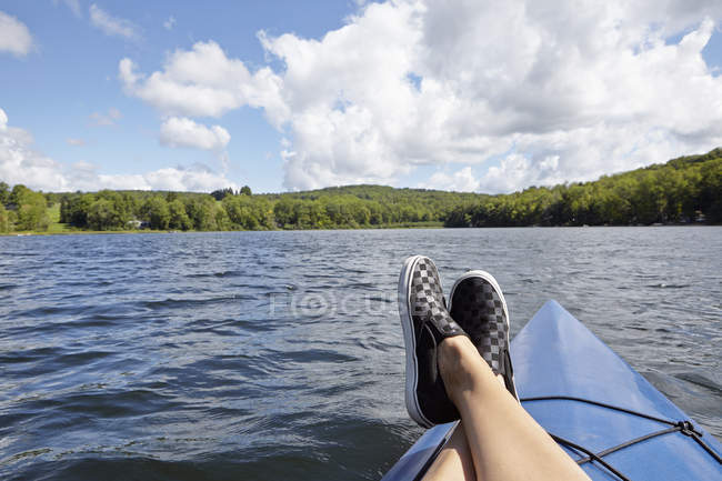 Ноги на каное з видом на озеро і зелений ліс — стокове фото