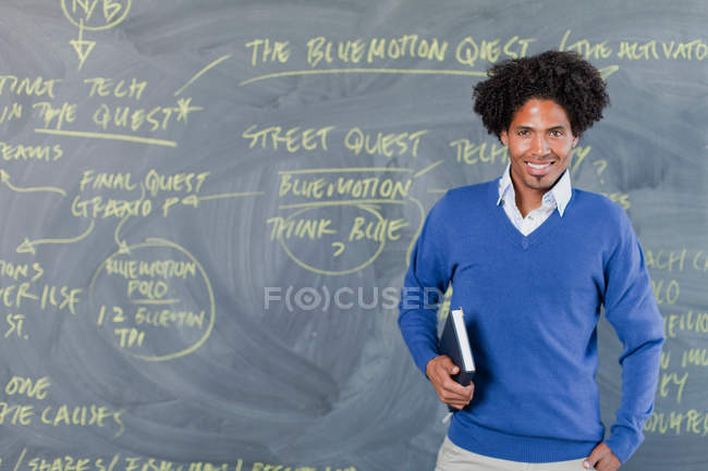 Teacher standing by chalkboard — Stock Photo