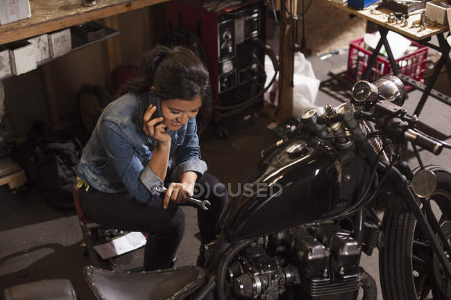 Mechanikerin benutzt Handy in Werkstatt — Stockfoto