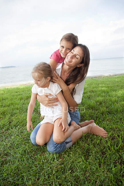 Girls and mother hugging outdoors — Stock Photo