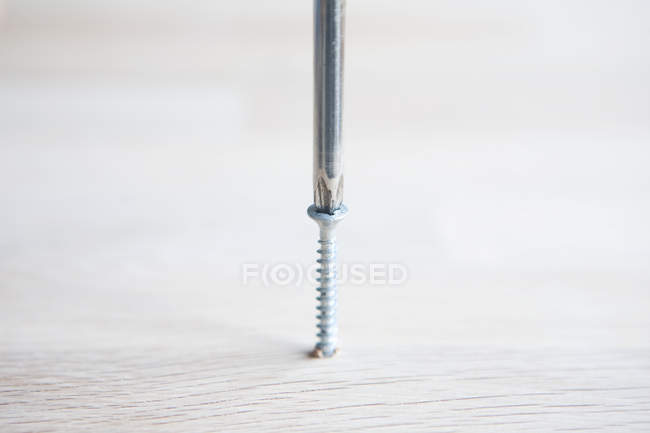Close up of Screwdriver and screw in wooden surface — Stock Photo