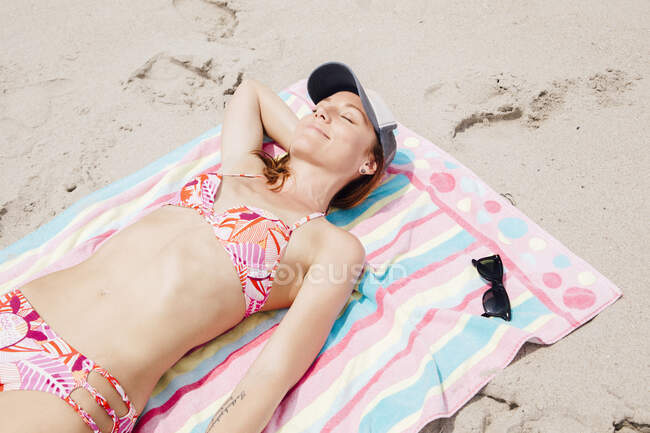 Жінка середнього віку лежить на пляжі — стокове фото