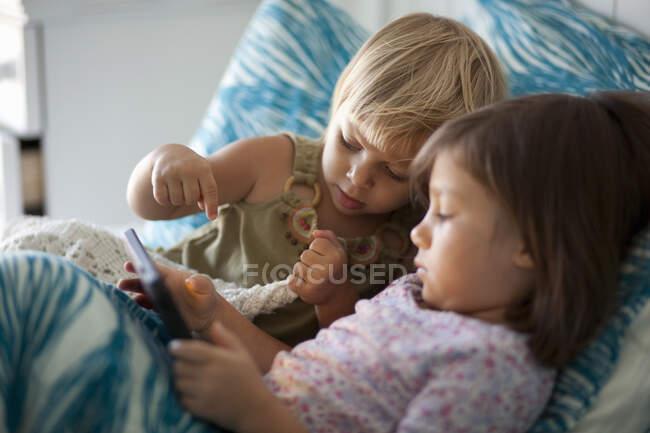 Mädchen und Kleinkind-Schwester sitzen mit digitalem Tablet im Bett — Stockfoto
