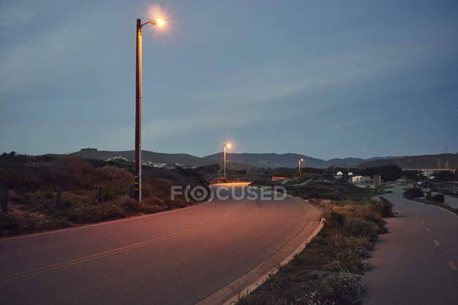 Lampadaires sur route sinueuse au crépuscule — Photo de stock