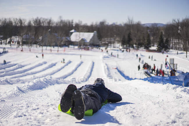 Man using crazy carpet type sled to slide down hill, Montreal, Quebec, Canada — Stock Photo