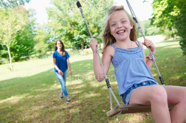 Girl playing on swing in backyard, focus on foreground — Stock Photo