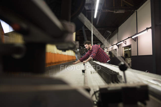 Giovane tessitore maschio che lavora presso la vecchia tessitrice in fabbrica tessile — Foto stock