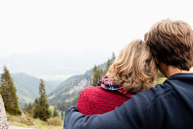Мужчина обнимает женщину, они смотрят пейзаж — стоковое фото