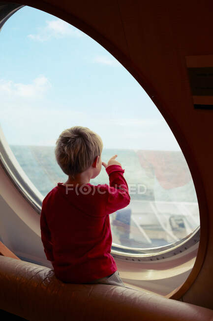 Junge bewundert Ozean vom Schiffsfenster aus — Stockfoto