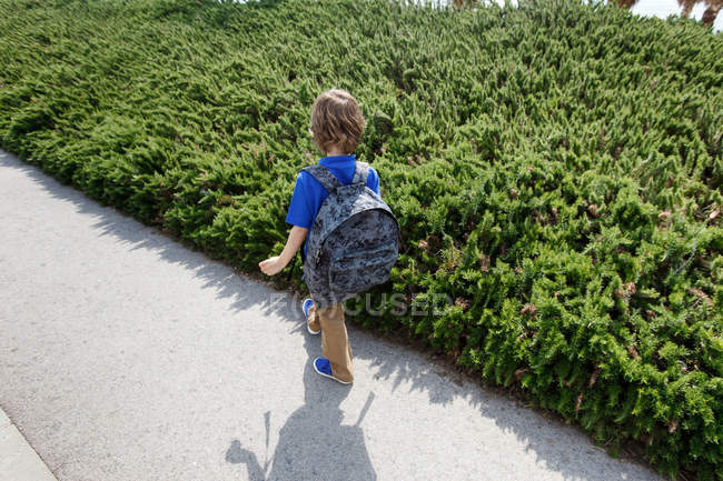 Мальчик прогуливается по кустам на улице — стоковое фото