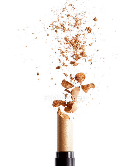 Exploding golden lipstick isolated on white background — Stock Photo