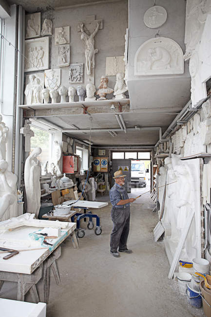 Trabalhador de pé em loja de escultura de alívio — Fotografia de Stock