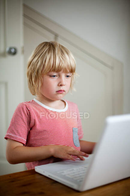 Мальчик с ноутбуком на столе — стоковое фото